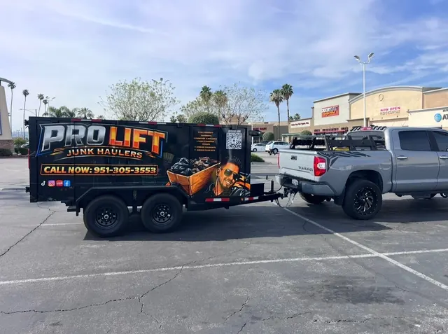 Silver pickup towing the black Pro Lift trailer through a shopping center lot