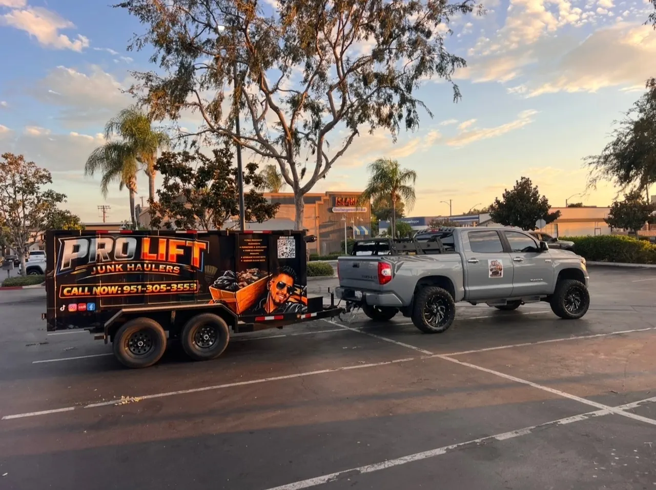 Pro Lift truck and branded dump trailer parked at sunset